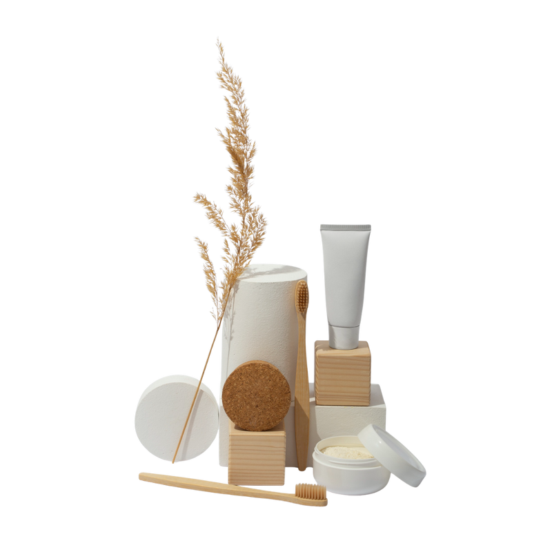 Collection of eco-friendly products including a toothbrush, containers, and a tube on a white background.