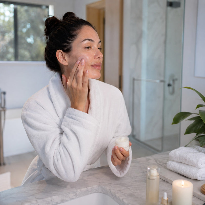 Woman applying cream to her face in a bathroom setting